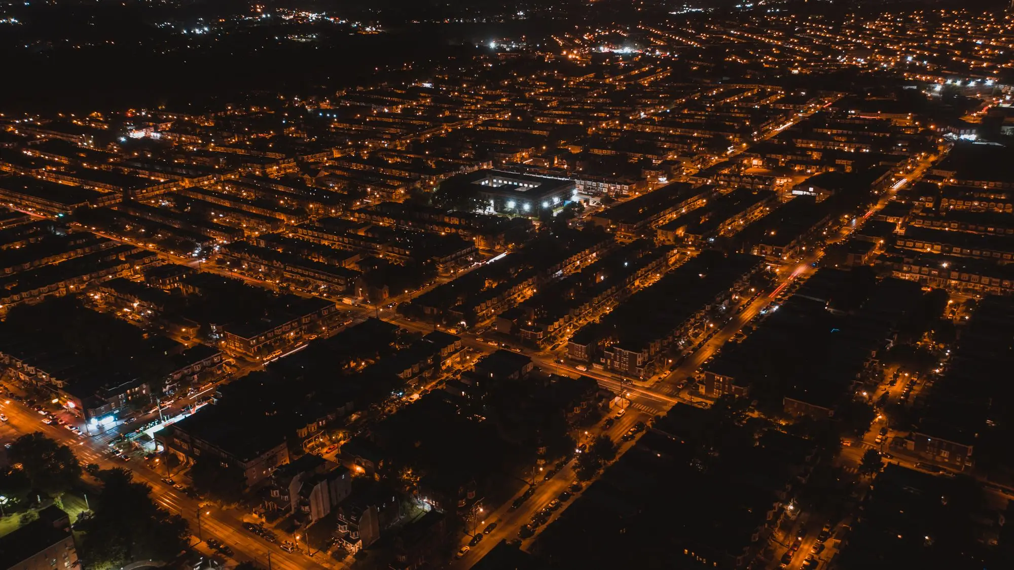 An aerial view of a town at night, its streets picked out in light