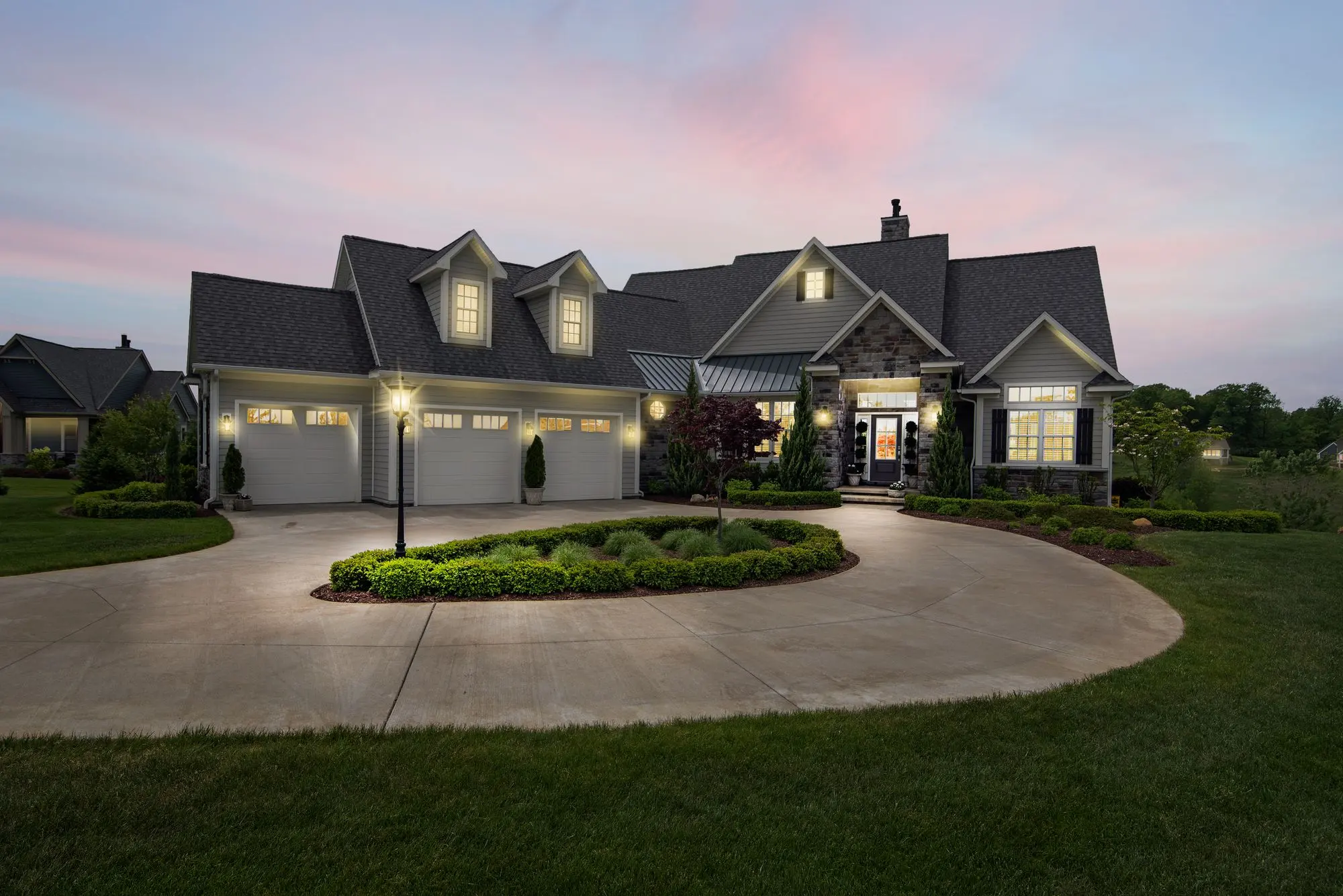 A modern single-storey house at dusk with warm light coming from the windows and the eaves