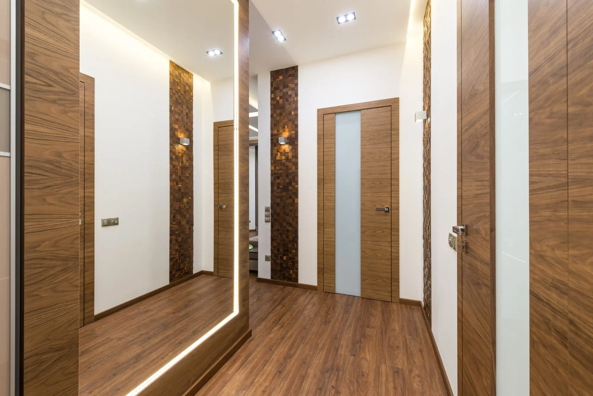 A contemporary hallway with wooden detailing and warm concealed lighting