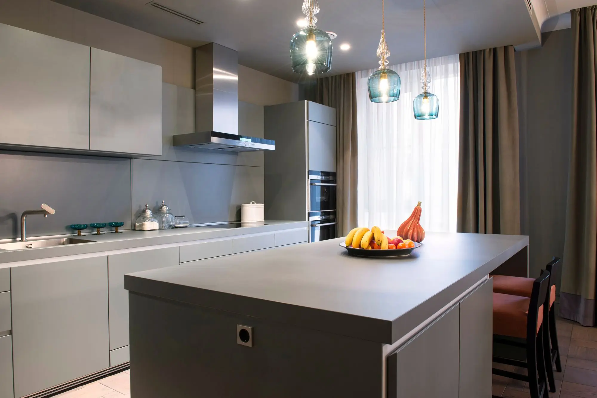 A contemporary kitchen with a long island and a row of pendant lights