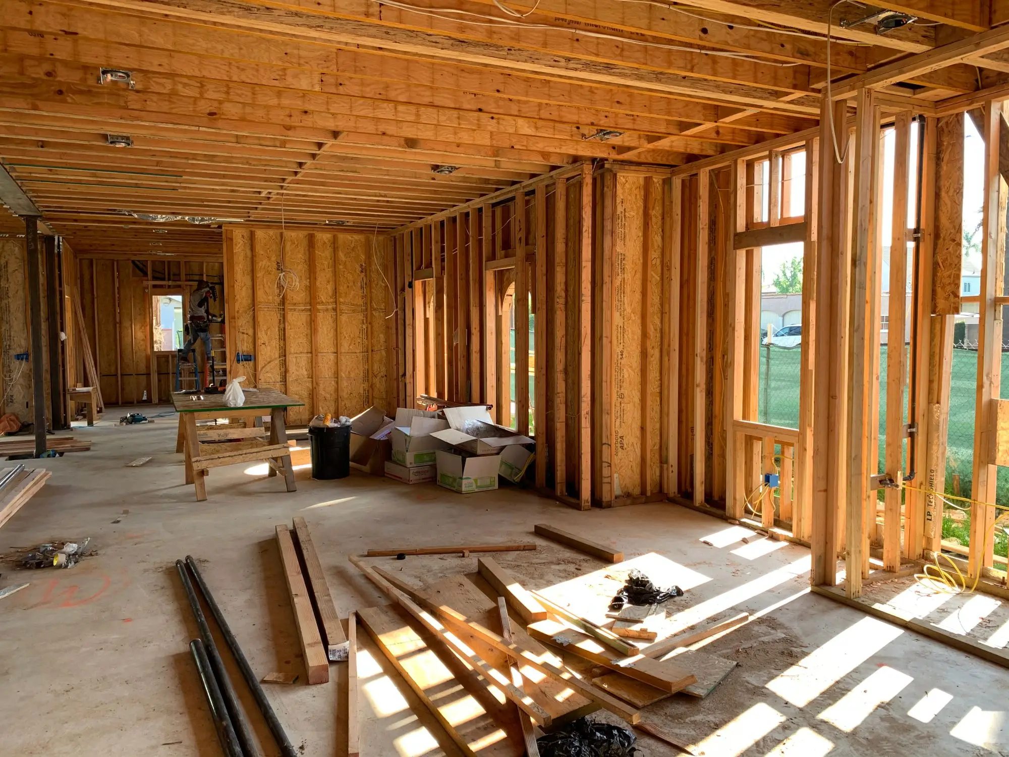 The inside of a house taken back to its timber framing, lit by daylight through open window openings
