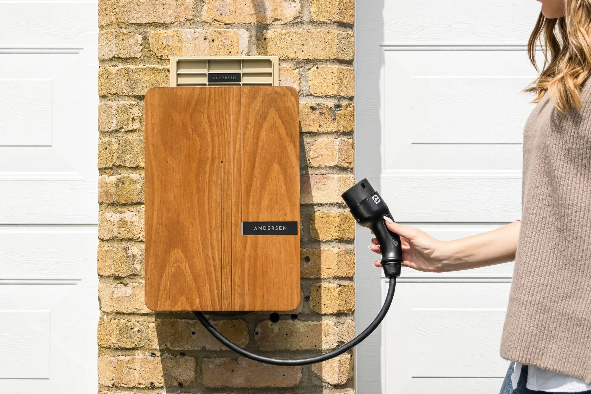 A wall-mounted home electric-vehicle charger on a brick wall