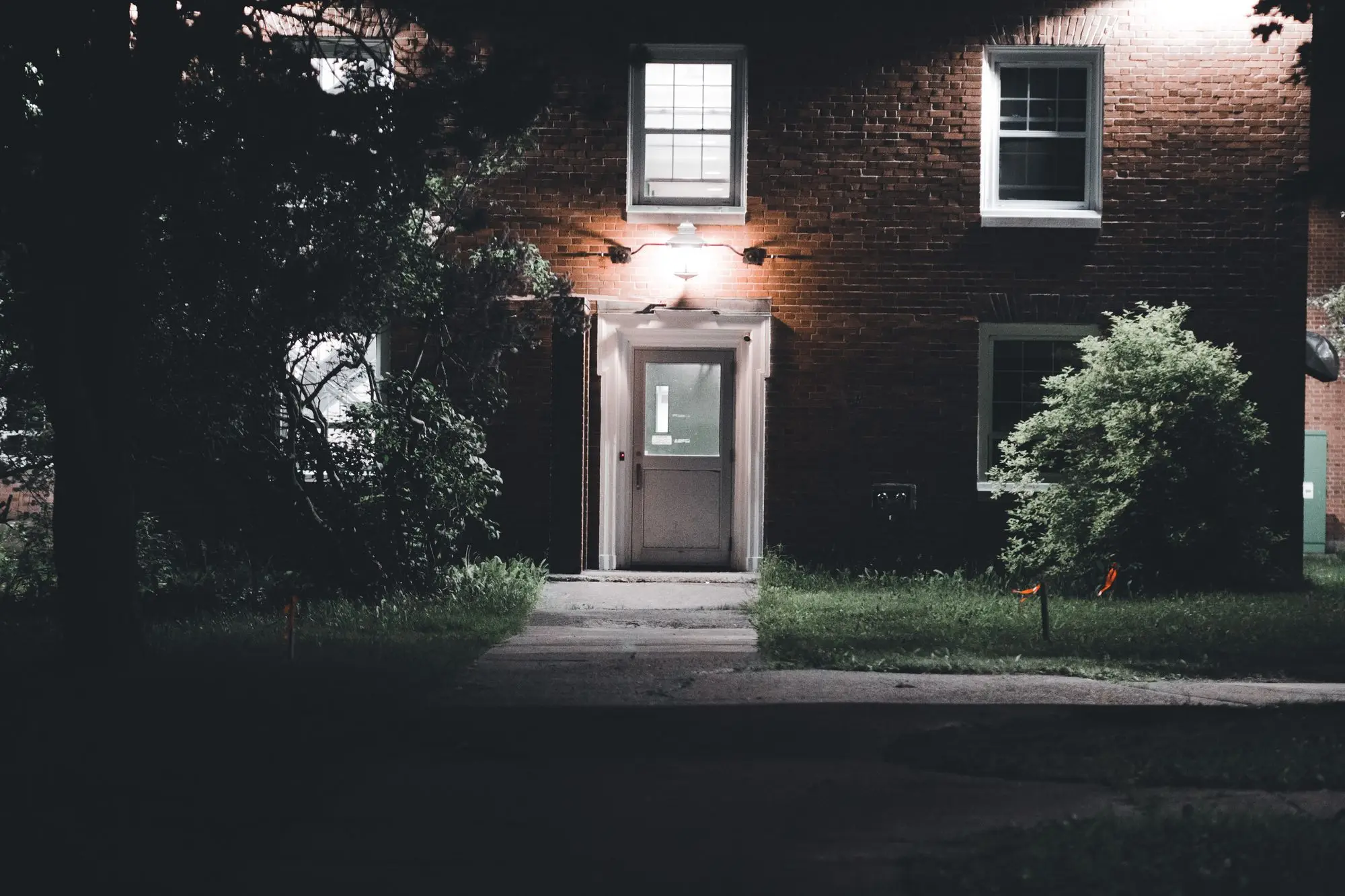 A brick house at night with the porch and windows still lit