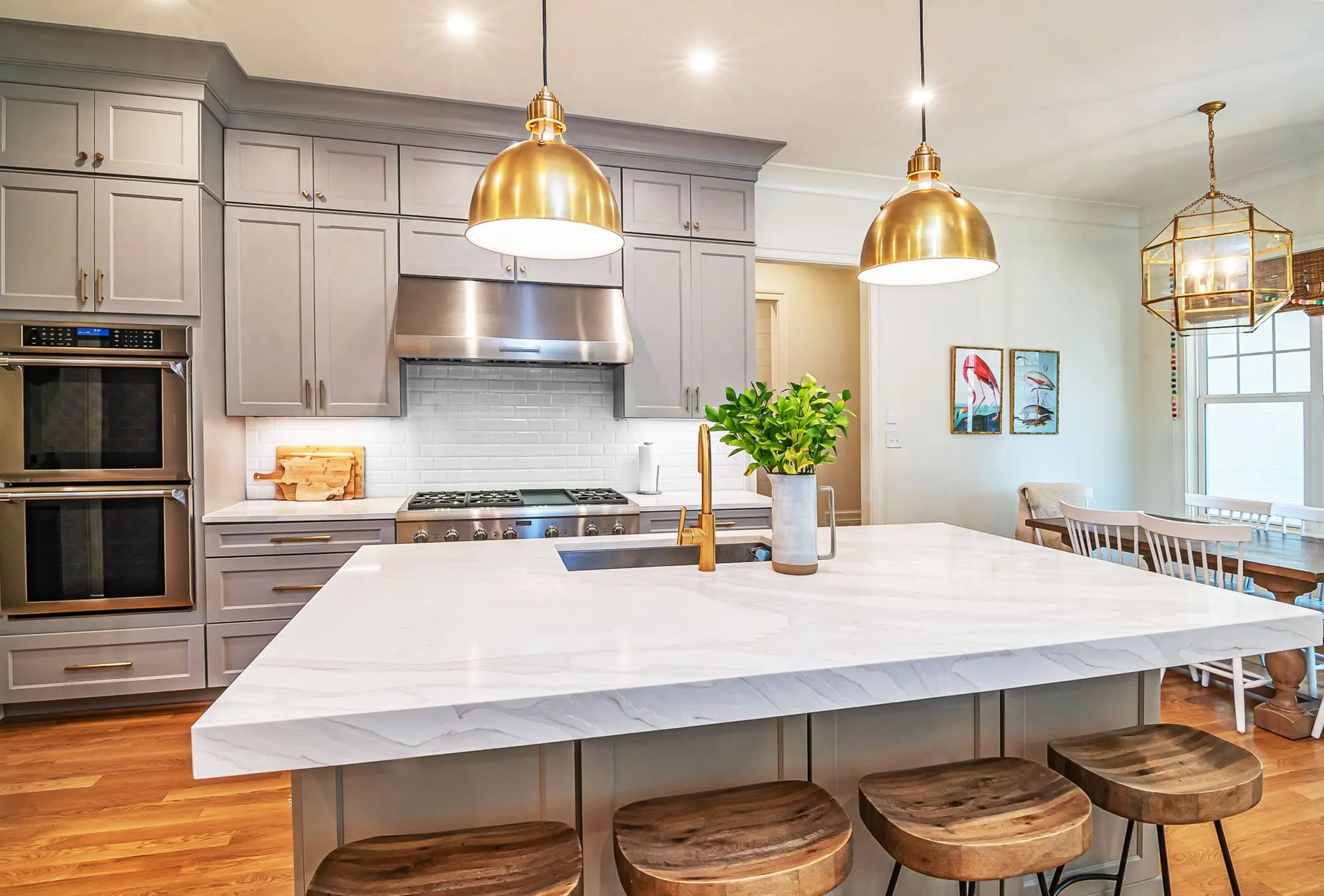 A kitchen with a marble island lit by three warm pendant fittings