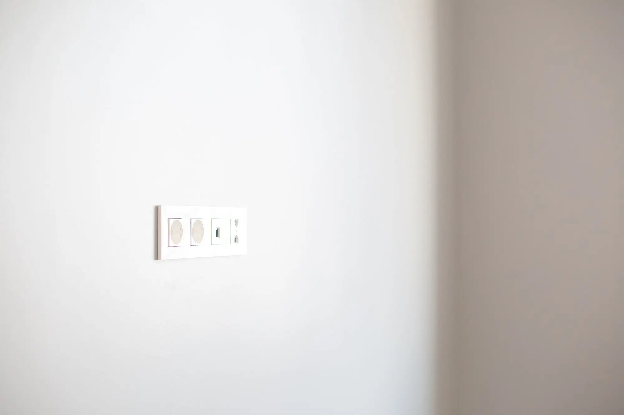 A single modern electrical outlet on a plain white wall