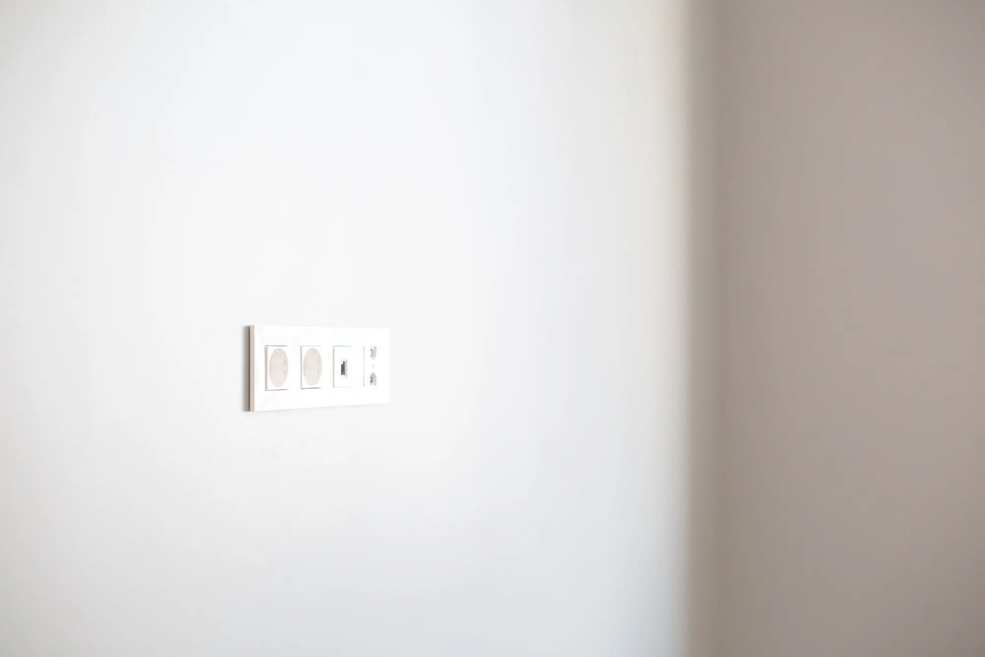 A single modern electrical outlet on a plain white wall