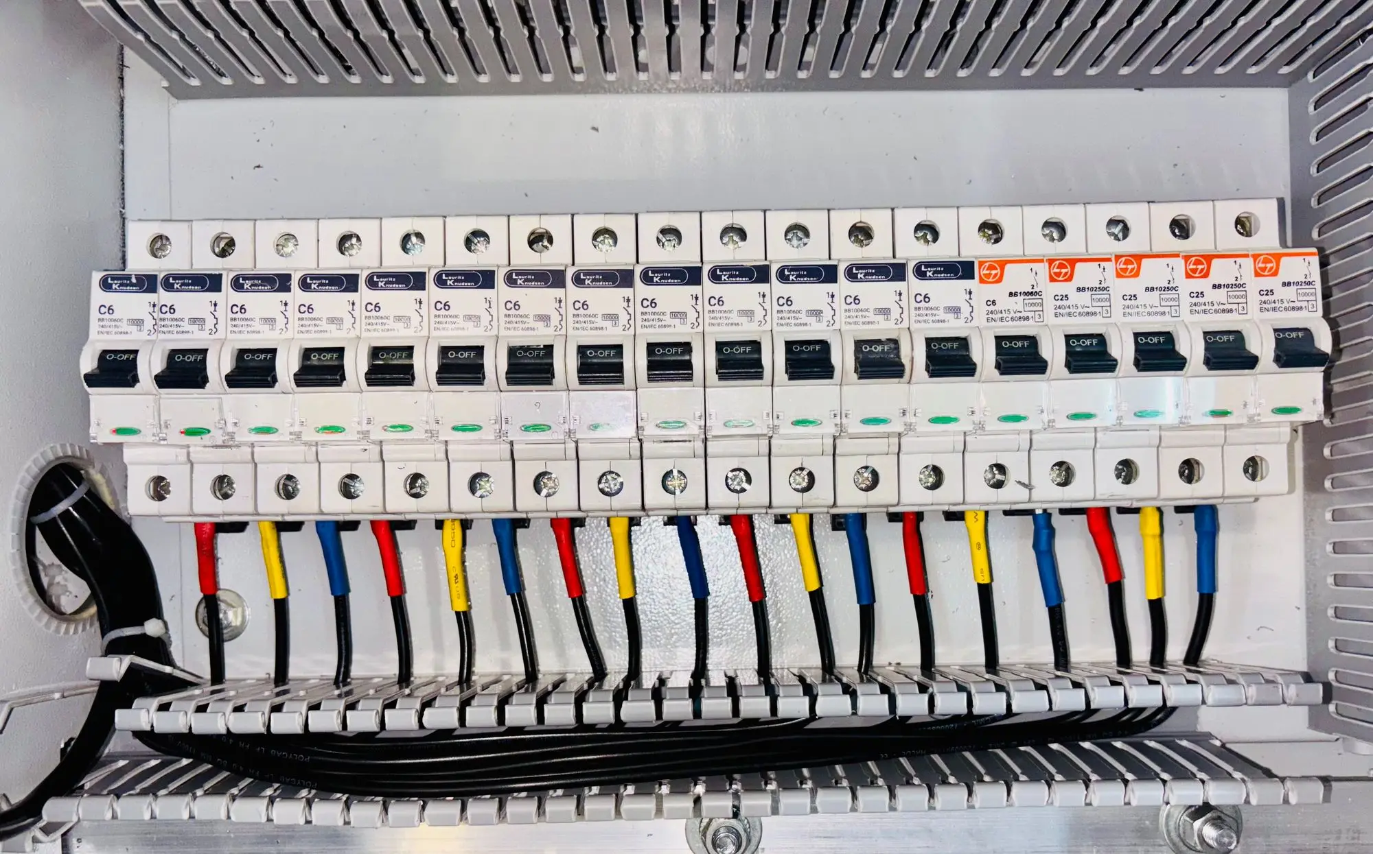 An open breaker panel with neatly dressed, colour-coded conductors