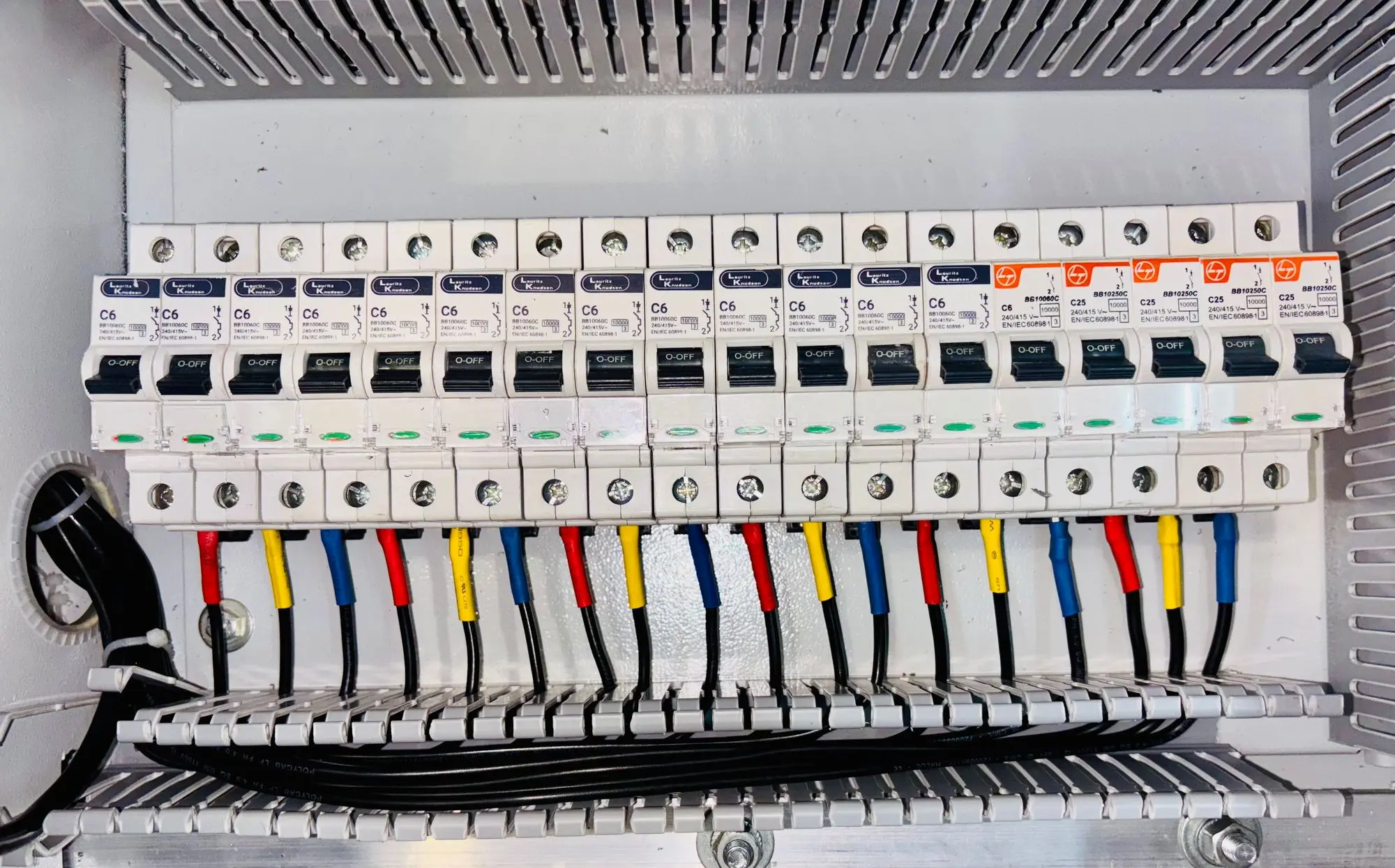 An open breaker panel with neatly dressed, colour-coded conductors