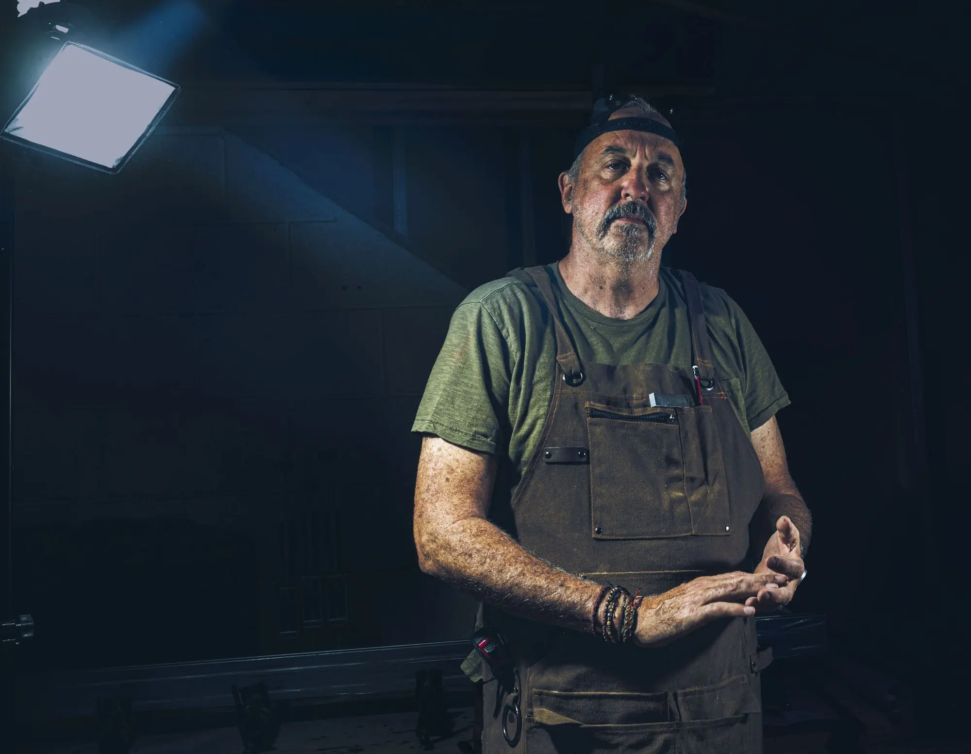 A portrait of an experienced tradesperson in overalls in a workshop